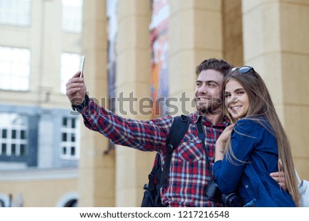 Happy couple of tourists taking selfie in showplace of city.