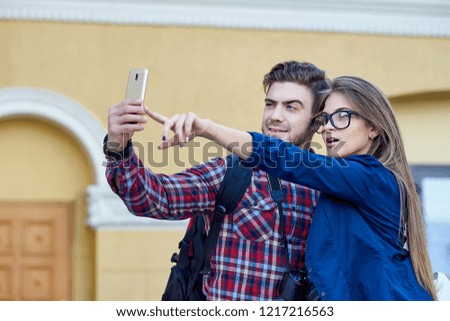Happy couple of tourists taking selfie in showplace of city. Man and woman making photo on city background.