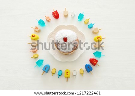 Image of jewish holiday Hanukkah with wooden dreidels colection (spinning top) and doughnut over white background