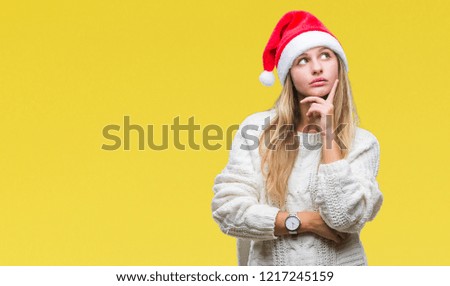 Young beautiful blonde woman wearing christmas hat over isolated background with hand on chin thinking about question, pensive expression. Smiling with thoughtful face. Doubt concept.