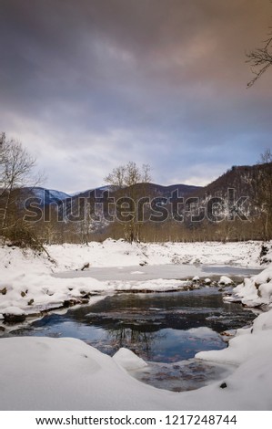 Snow covered natural pastoral landscape of Turkish countryside during cold winter season in Marmara region of the country with hills, woodland, lake and village road