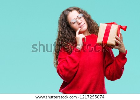 Young brunette girl holding a gift over isolated background serious face thinking about question, very confused idea