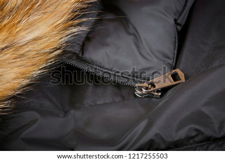 Fur and zipper on the black background. Macro shot