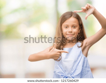 Brunette hispanic girl smiling making frame with hands and fingers with happy face. Creativity and photography concept.