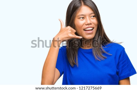 Young asian woman over isolated background smiling doing phone gesture with hand and fingers like talking on the telephone. Communicating concepts.