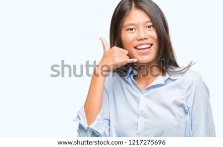 Young asian business woman over isolated background smiling doing phone gesture with hand and fingers like talking on the telephone. Communicating concepts.