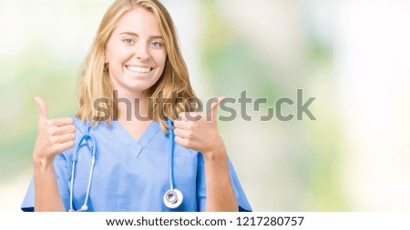 Beautiful young doctor woman wearing medical uniform over isolated background success sign doing positive gesture with hand, thumbs up smiling and happy. Looking at the camera with cheerful expression