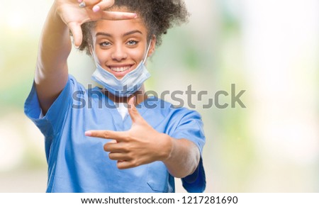 Young afro american doctor woman over isolated background smiling making frame with hands and fingers with happy face. Creativity and photography concept.
