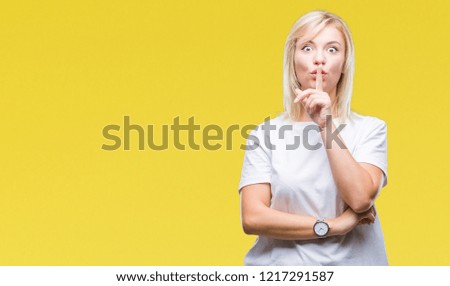 Young beautiful blonde woman wearing white t-shirt over isolated background asking to be quiet with finger on lips. Silence and secret concept.
