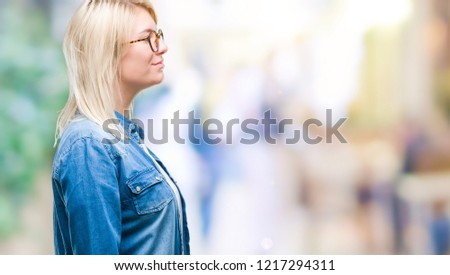 Young beautiful blonde woman wearing glasses over isolated background looking to side, relax profile pose with natural face with confident smile.