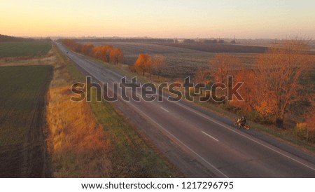 Aerial: motorbike on the asphalt road at sunset time
