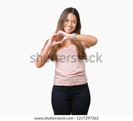 Young beautiful brunette woman wearing pink t-shirt over isolated background smiling in love showing heart symbol and shape with hands. Romantic concept.
