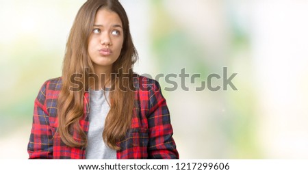 Young beautiful brunette woman wearing a jacket over isolated background making fish face with lips, crazy and comical gesture. Funny expression.