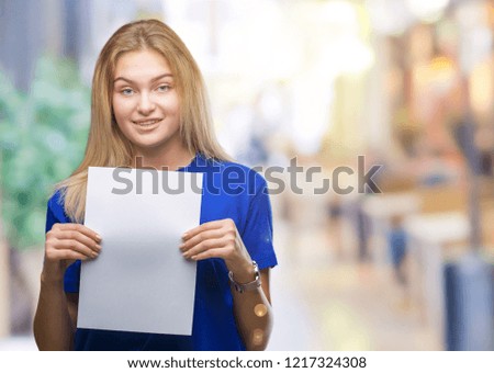Young caucasian woman holding blank paper sheet over isolated background with a happy face standing and smiling with a confident smile showing teeth