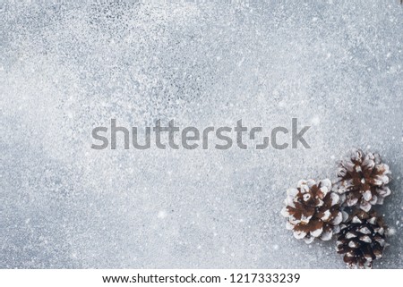 Pine cones on a gray background with the effect of falling snow. Texture subtext