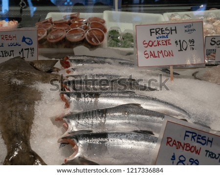 Fresh sockeye salmon, rainbow trout, and halibut and sale signs and prices in ice at a fish market storefront