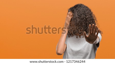 Beautiful young hispanic woman wearing glasses covering eyes with hands and doing stop gesture with sad and fear expression. Embarrassed and negative concept.