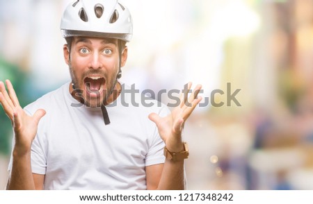 Young handsome man wearing cyclist safety helmet over isolated background celebrating crazy and amazed for success with arms raised and open eyes screaming excited. Winner concept