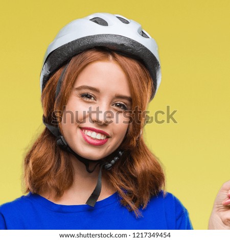 Young beautiful woman wearing cyclist helmet over isolated background with a big smile on face, pointing with hand and finger to the side looking at the camera.