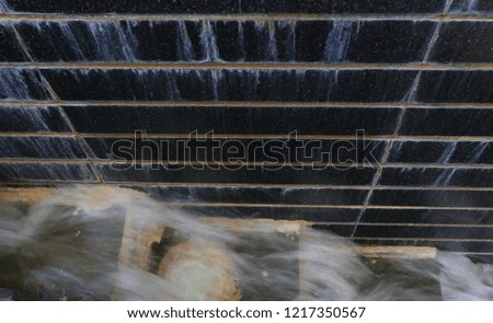Blurred motion of water flows from step to step and black stone wall with water falls, top view picture