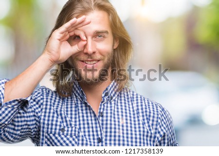 Young handsome man with long hair over isolated background doing ok gesture with hand smiling, eye looking through fingers with happy face.