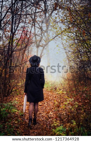 Woman in a black coat and hat in foggy weather