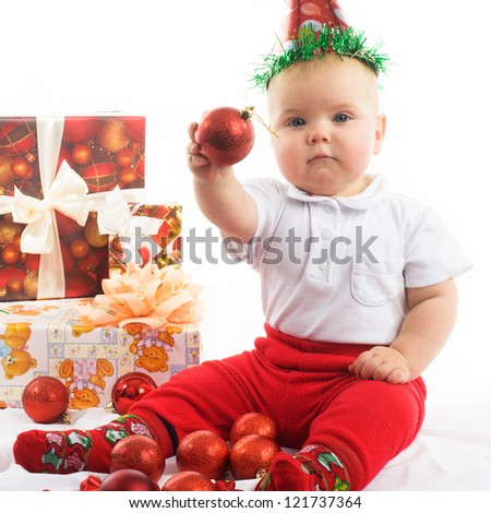 Happy, cute Christmas baby with baubles and gifts isolated on white.