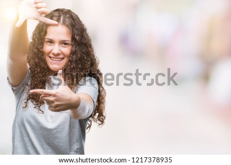 Beautiful young brunette curly hair girl wearing casual look over isolated background smiling making frame with hands and fingers with happy face. Creativity and photography concept.