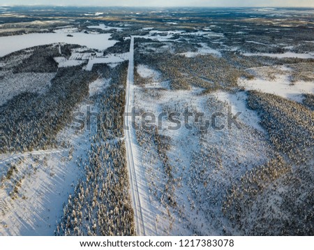 Aerial view of snow winter road and pine woods in Finland, Lapland