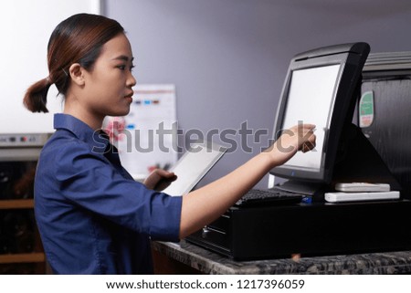 Pretty young waitress entering order details in computer