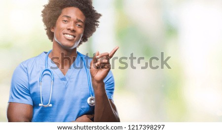 Afro american surgeon doctor man over isolated background with a big smile on face, pointing with hand and finger to the side looking at the camera.
