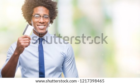 Afro american man holding credit card over isolated background with a happy face standing and smiling with a confident smile showing teeth