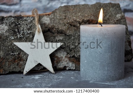 Burning candle, star and wood billet on concrete