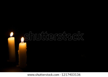 Two candles on dark background. Lighting candles on black. Yellow wax candle with warm flame. In memoriam banner template with text space. Religious or mourning backdrop. Yellow candlelight photo 