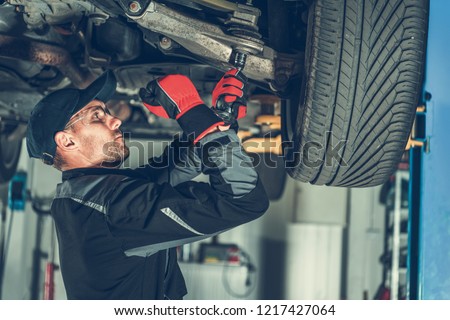 Caucasian Car Mechanic Adjusting Tension in Vehicle Suspension Element. Professional Automotive Service. Royalty-Free Stock Photo #1217427064