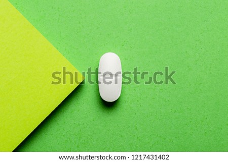 close up of a white pill in green background