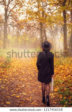 Woman in a black coat and hat in foggy weather