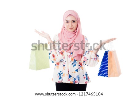 Young lady in modern muslim attire holding a golden paper bag isolated with white background.