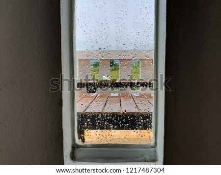 View of grass field and mountain through water drops on glass window