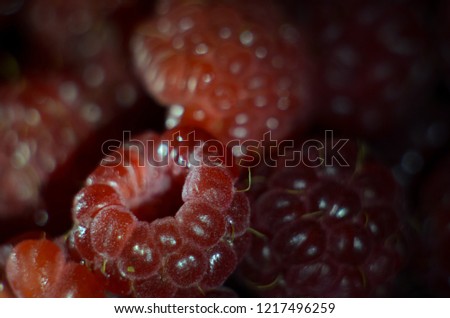 Beautiful juicy red raspberry berry on black background with backlight. Macrophotography of fruit. Picture on your desktop or Wallpapers.