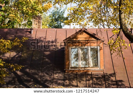Dormer window in the old private house under the autumn trees
