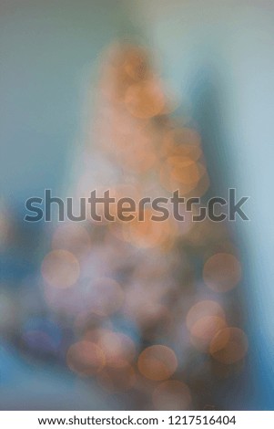 Christmas tree defocused bokeh silhouette with illuminated  shimmering garlands against a blue wall