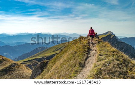 nice senior woman, hiking in fall, autumn  on the ridge of the Nagelfluh chain near Oberstaufen, Allgaeu Area, Bavaria, Germany, Hochgrats summit in the background Royalty-Free Stock Photo #1217543413