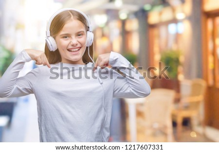 Young beautiful girl wearing headphones listening to music over isolated background looking confident with smile on face, pointing oneself with fingers proud and happy.