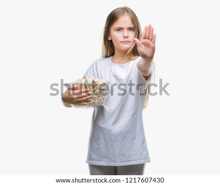 Young beautiful girl eating popcorn snack isolated background with open hand doing stop sign with serious and confident expression, defense gesture