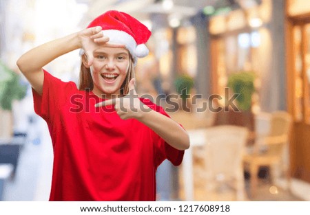 Young beautiful girl wearing christmas hat over isolated background smiling making frame with hands and fingers with happy face. Creativity and photography concept.