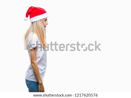 Young beautiful blonde woman christmas hat over isolated background looking to side, relax profile pose with natural face with confident smile.