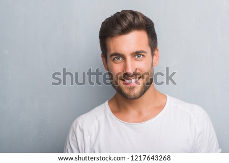 Handsome young man over grey grunge wall with a happy face standing and smiling with a confident smile showing teeth Royalty-Free Stock Photo #1217643268