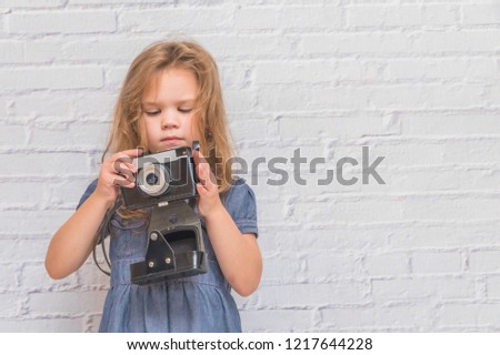 the girl, child with vintage camera on white brick wall background