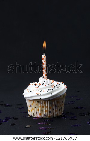 Image of a yummy cupcake with candle on dark background